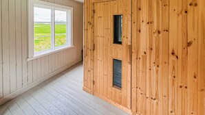 A room with wooden walls, a large window with a view of a green field, and a door with a small window. - Beautiful home in Gunnarsbytorp with sauna (Gunnarsbytorp)