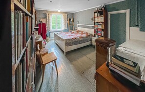 Une chambre à coucher avec un lit, une bibliothèque, un bureau et une chaise.