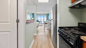 Una cocina con estufa, refrigerador y comedor con mesa y sillas.