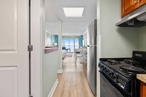 A kitchen with a stove, refrigerator, and a dining area with a table and chairs.