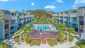 A hotel with a central pool, multiple balconies, and a well-maintained garden. - Ocean Forest Villas C-114 (Myrtle Beach)