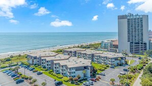 A coastal hotel with multiple buildings, a parking lot, and a beach view. - Ocean Forest Villas C-114 (Myrtle Beach)