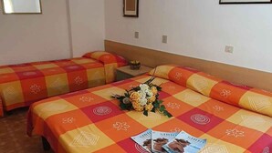 A hotel room with two beds, a small table, and a wall-mounted picture.