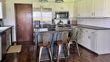 A kitchen with white cabinets, a wooden door, and a central island with bar stools.