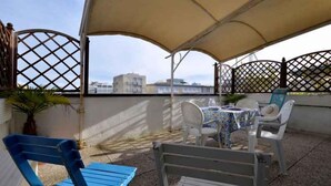 Un patio al aire libre con una mesa y sillas, una silla azul y un banco blanco.
