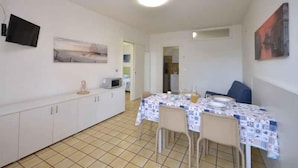 Una cocina compacta con armarios blancos, un microondas y un comedor con mesa dispuesta para dos.