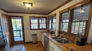 Una cocina con armarios de madera, un lavamanos y una ventana con persianas.