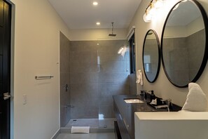 A modern bathroom with a glass-enclosed shower, a large mirror, and a vanity with a towel.