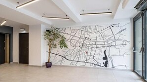 En moderne lobby med et stort vægkort, en potteplante og en glasdør.