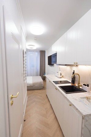 Ein kleines Hotelzimmer mit Küchenzeile, einem Bett und einem Badezimmer.