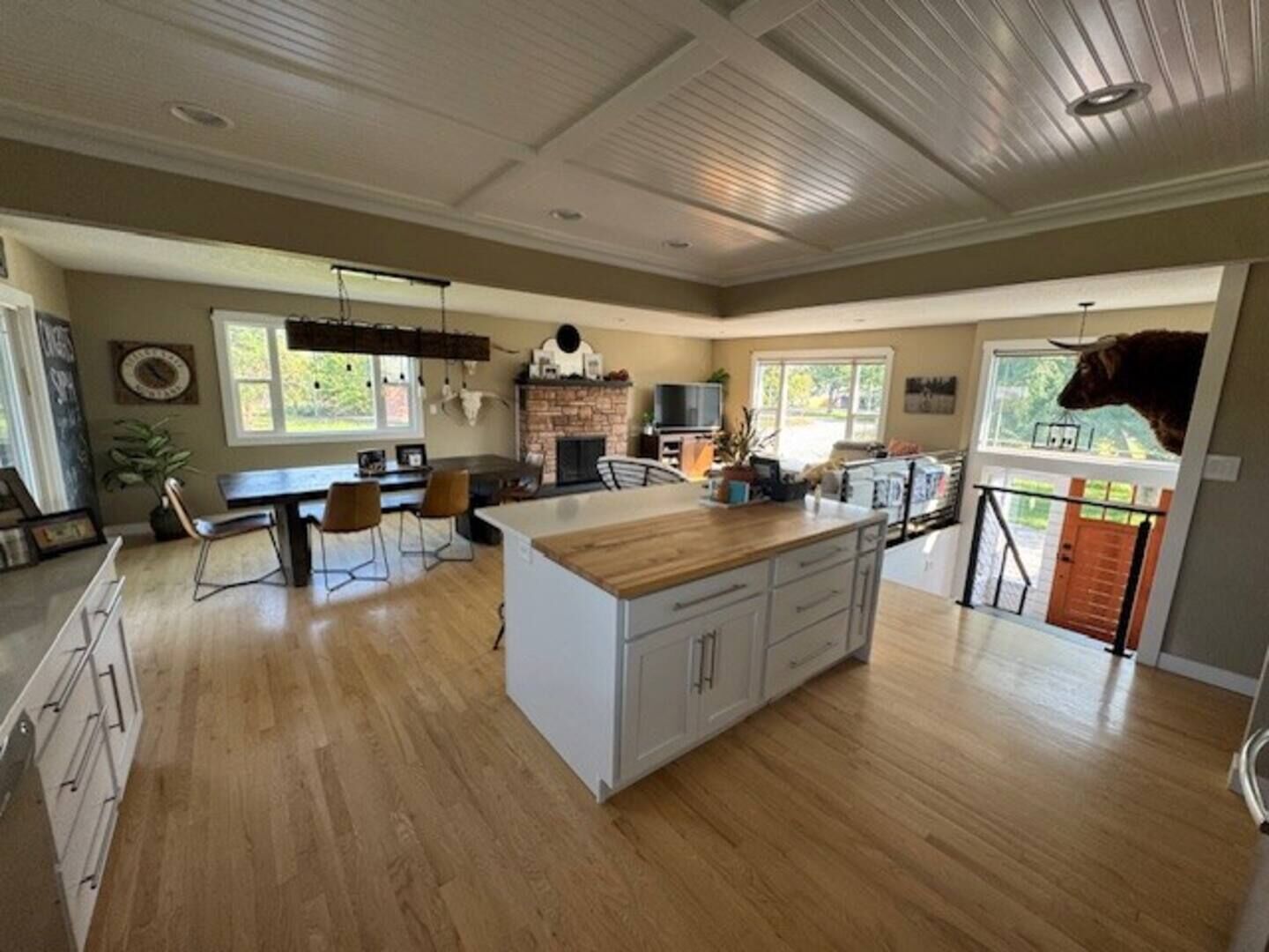 Une cuisine spacieuse dotée d’un grand îlot central, de planchers en bois et d’une cheminée en pierre.