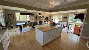 A spacious kitchen with a large island, wooden flooring, and a stone fireplace.