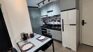 Una cucina compatta con elettrodomestici moderni, un tavolo da pranzo con sedie e un forno a microonde sopra il piano cottura.
