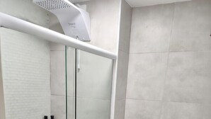 Un bagno con doccia vetrata, un water e uno scaffale in vetro con articoli da toilette.