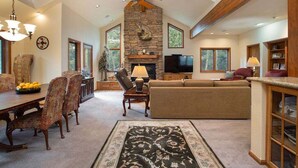 A spacious living room with a stone fireplace, a large sofa, and a dining area with a wooden table and chairs. - Streamside Lane: Riverside Frisco Home, Dog Friendly, Near Slopes (Frisco)