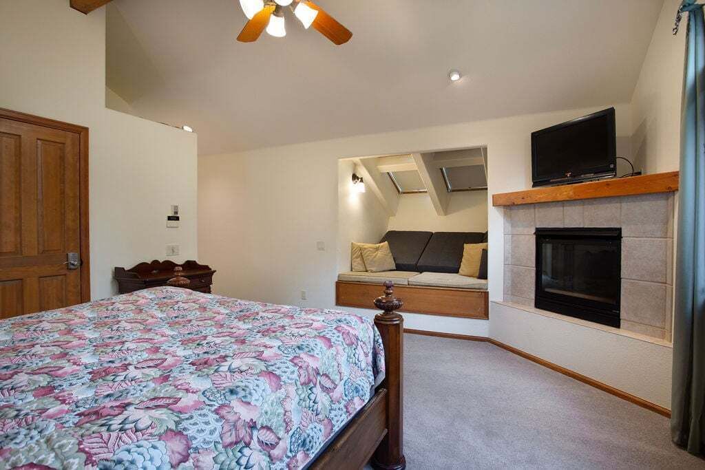 Une chambre à coucher comprenant un lit, une télévision, une cheminée et un ventilateur de plafond.