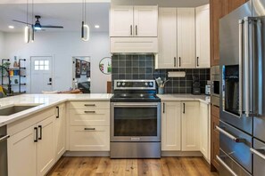 Una cocina moderna con armarios blancos, electrodomésticos de acero inoxidable y piso de madera.
