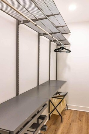 A room with a metal shelving unit, a table, and a hanging rack.