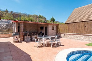 An outdoor patio with a barbecue area, a pool, and a wooden fence. - Nordic-style vacation home on the Costa del Sol—enjoy the Andalusian climate with a pool! (AN)