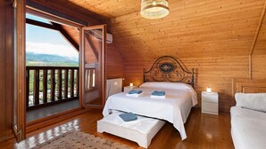 A wooden cabin bedroom with a bed, bedside tables, a hanging light fixture, and a view through an open door. - Nordic cottage on the Costa del Sol, enjoy the Andalusian climate with swimming pool! (AN)