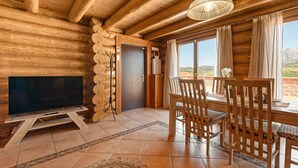 A wooden interior with a TV, dining table, chairs, and a view of the outdoors. - Nordic cottage on the Costa del Sol, enjoy the Andalusian climate with swimming pool! (AN)
