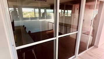 Uma porta de vidro com a palavra 'COWORKING' escrita, que dá acesso a um espaço interior com varanda.