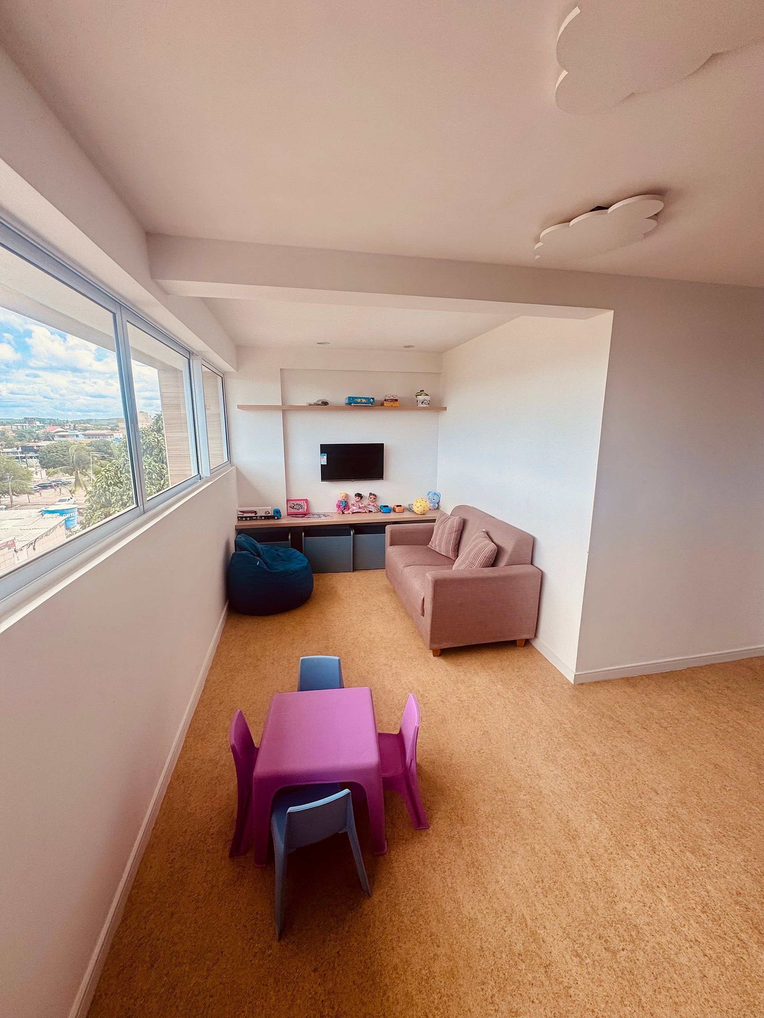 A modern living room with a sofa, a pink table, and a bean bag.