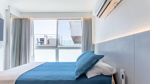 Camera d'albergo con un letto, tende, una finestra e un pannello di controllo a parete.