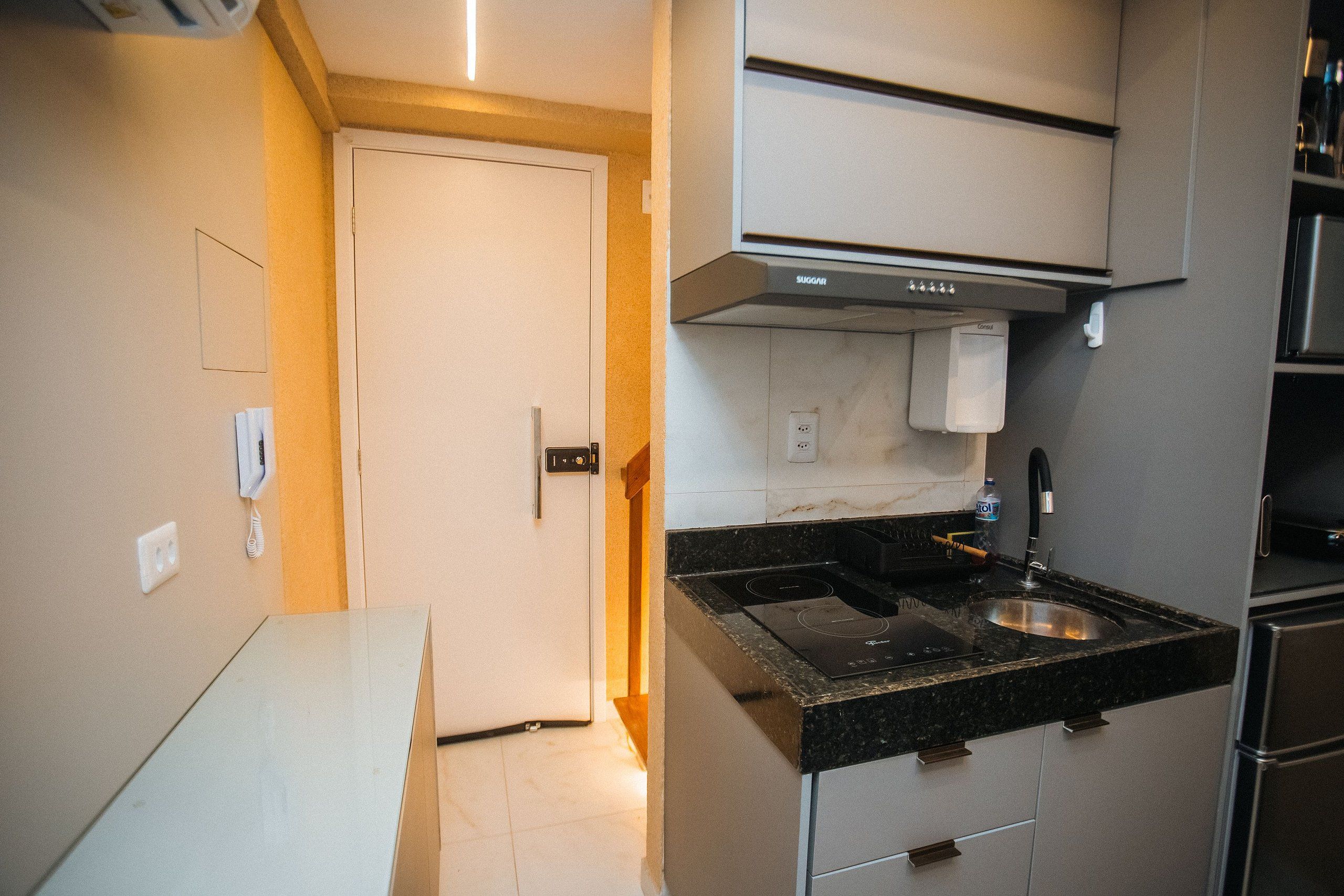 Uma cozinha compacta com fogão embutido, pia e micro-ondas.