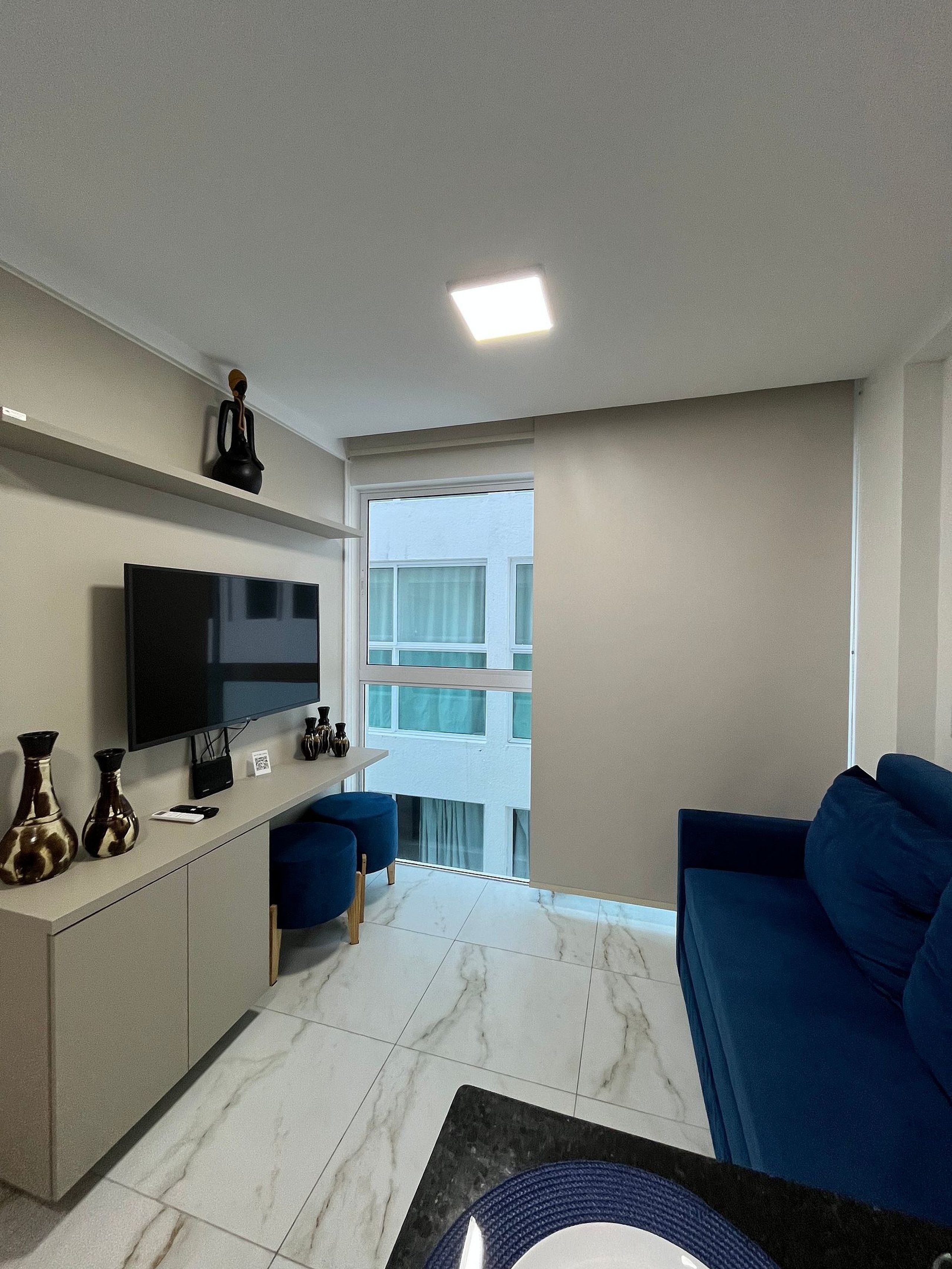 A modern living room with a flat-screen TV, a sofa, a coffee table, and a small dining area.