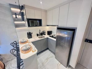 A modern kitchen with a stainless steel refrigerator, a microwave, and a coffee maker. - Essenza Porto de Galinhas - Flat na Praia (Ipojuca)