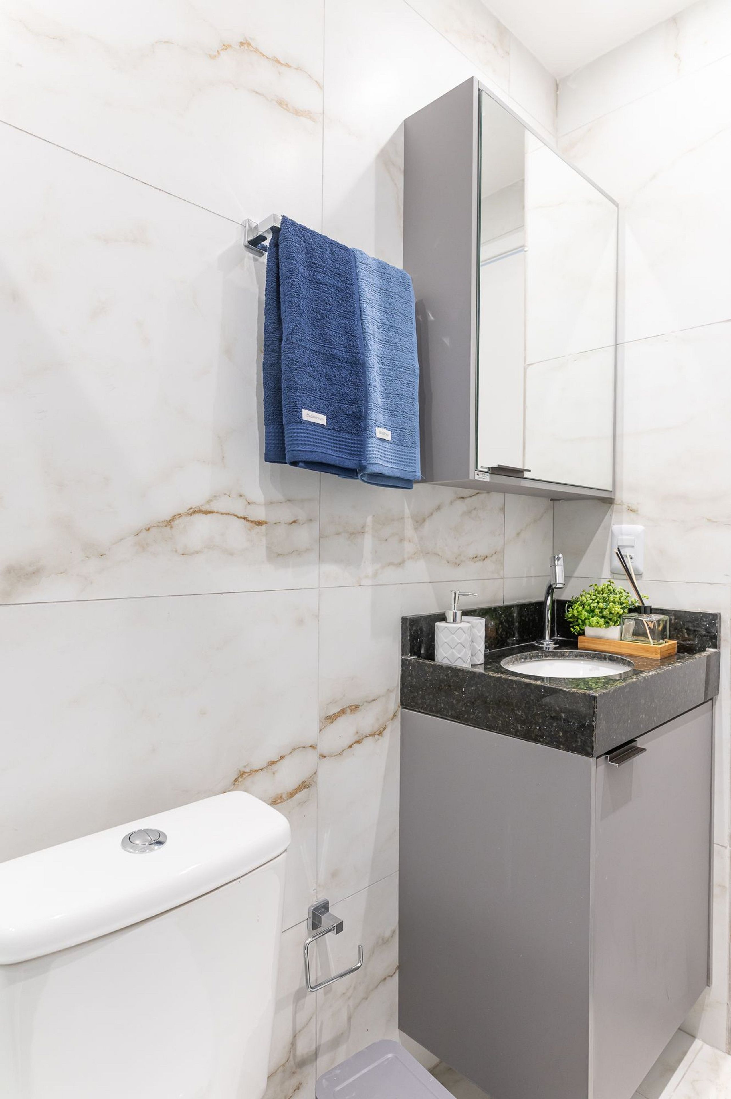 Een badkamer met toilet, wastafel, spiegel en handdoekhouder.