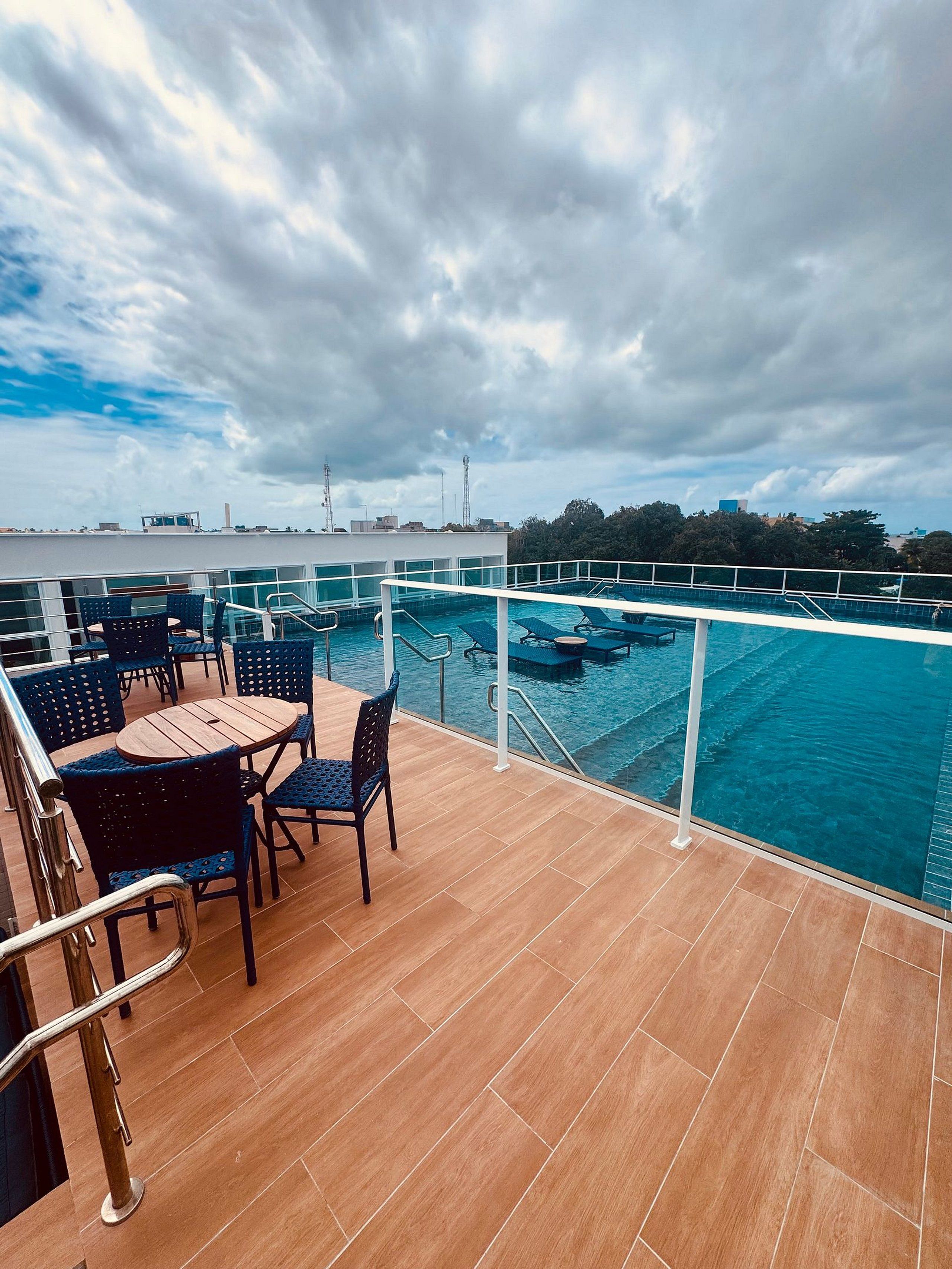 A deck with a pool, chairs, and a table.