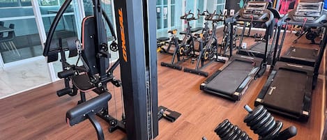 Una palestra con attrezzature per esercizi, tapis roulant e macchinari per pesi.