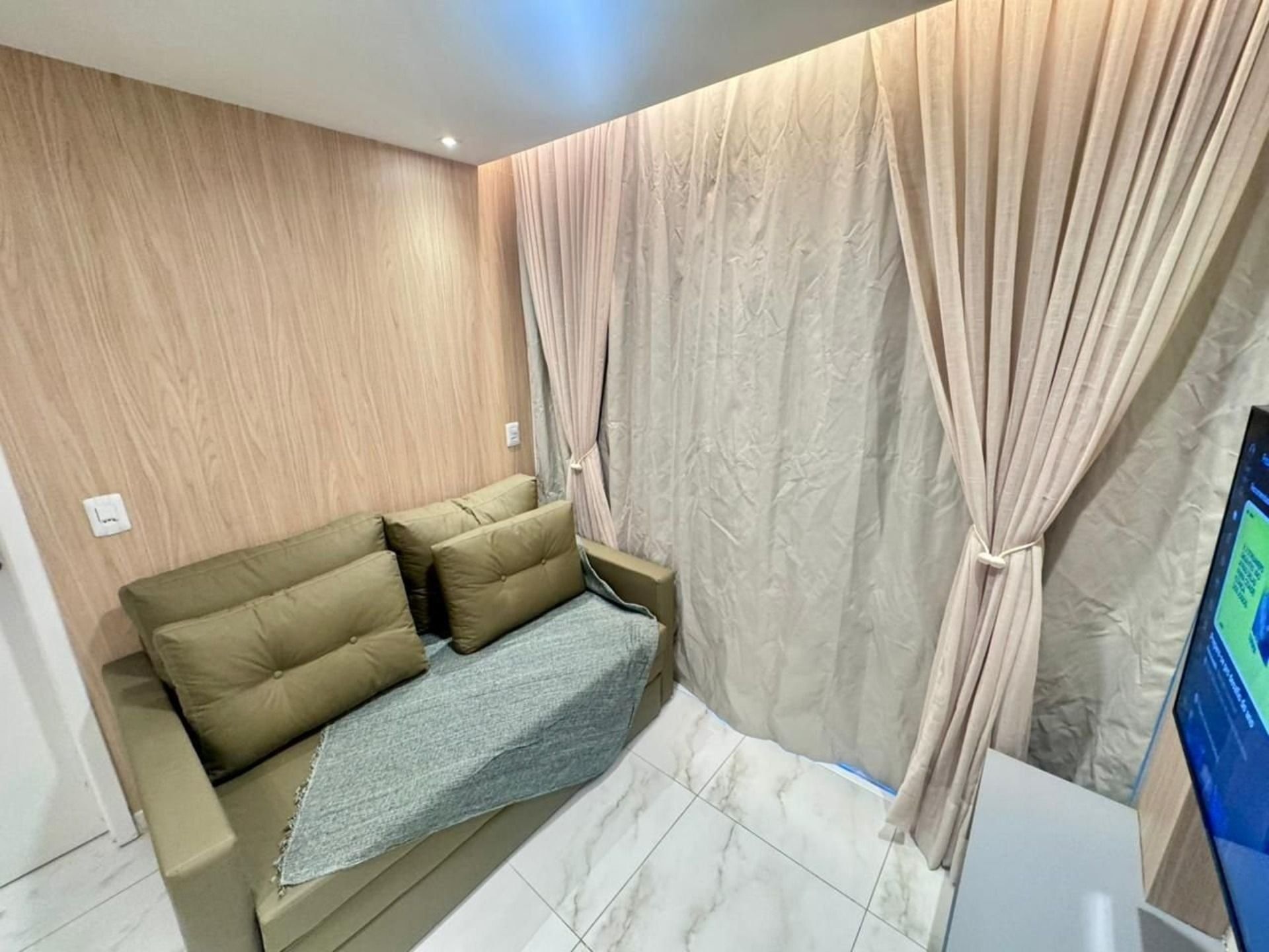 Una habitación moderna con sofá, cortinas y televisor.