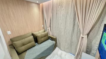 Una habitación moderna con sofá, cortinas y televisor.