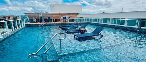Una piscina al aire libre, sillones reclinables de piscina
