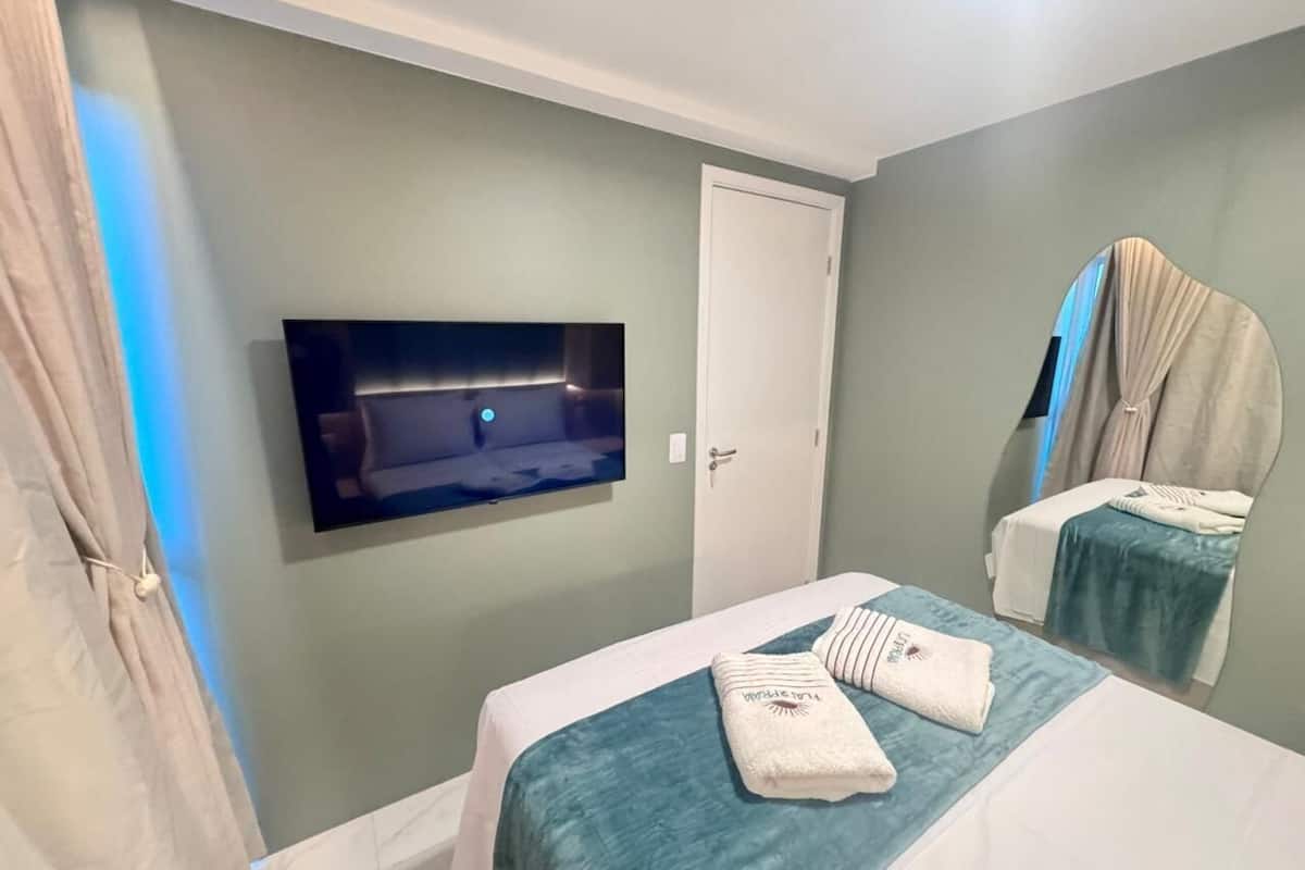 Hotellihuone, jossa on kaksi sänkyä, seinälle asennettu televisio ja ovi.