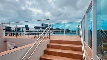 Una escalera conduce a una terraza en la azotea con asientos exteriores y vistas de la ciudad.