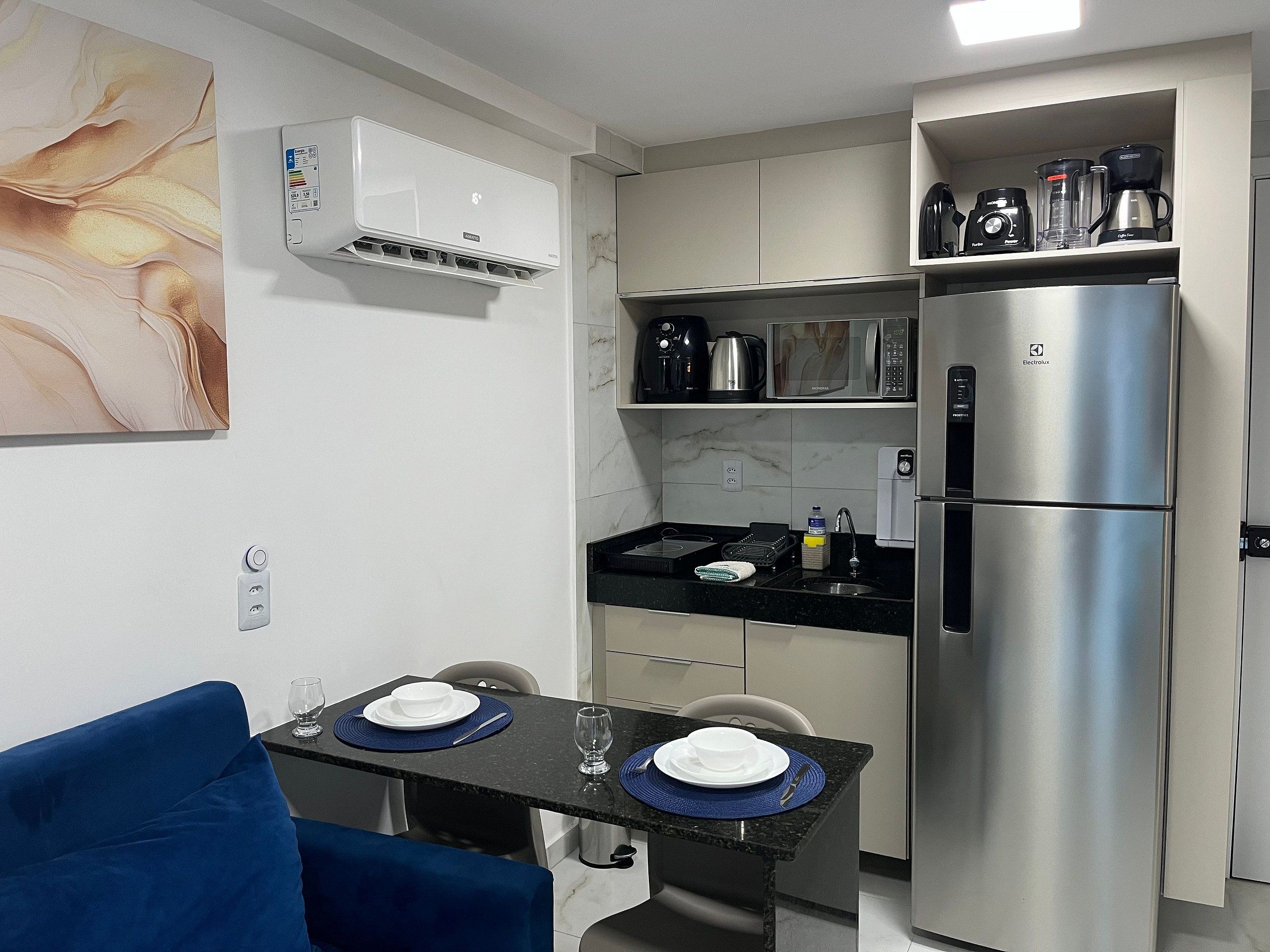 Cocina compacta con refrigerador, microondas y cafetera.