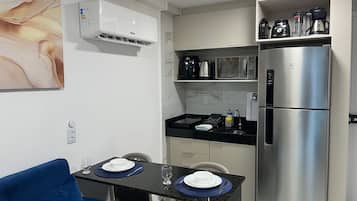 Cocina compacta con refrigerador, microondas y cafetera.