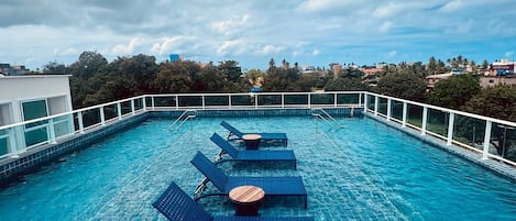 Una piscina al aire libre, sillones reclinables de piscina