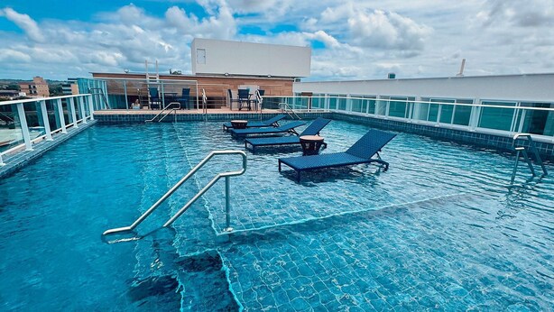 Una piscina sul tetto con acqua cristallina, sedie a sdraio e una ringhiera in vetro.