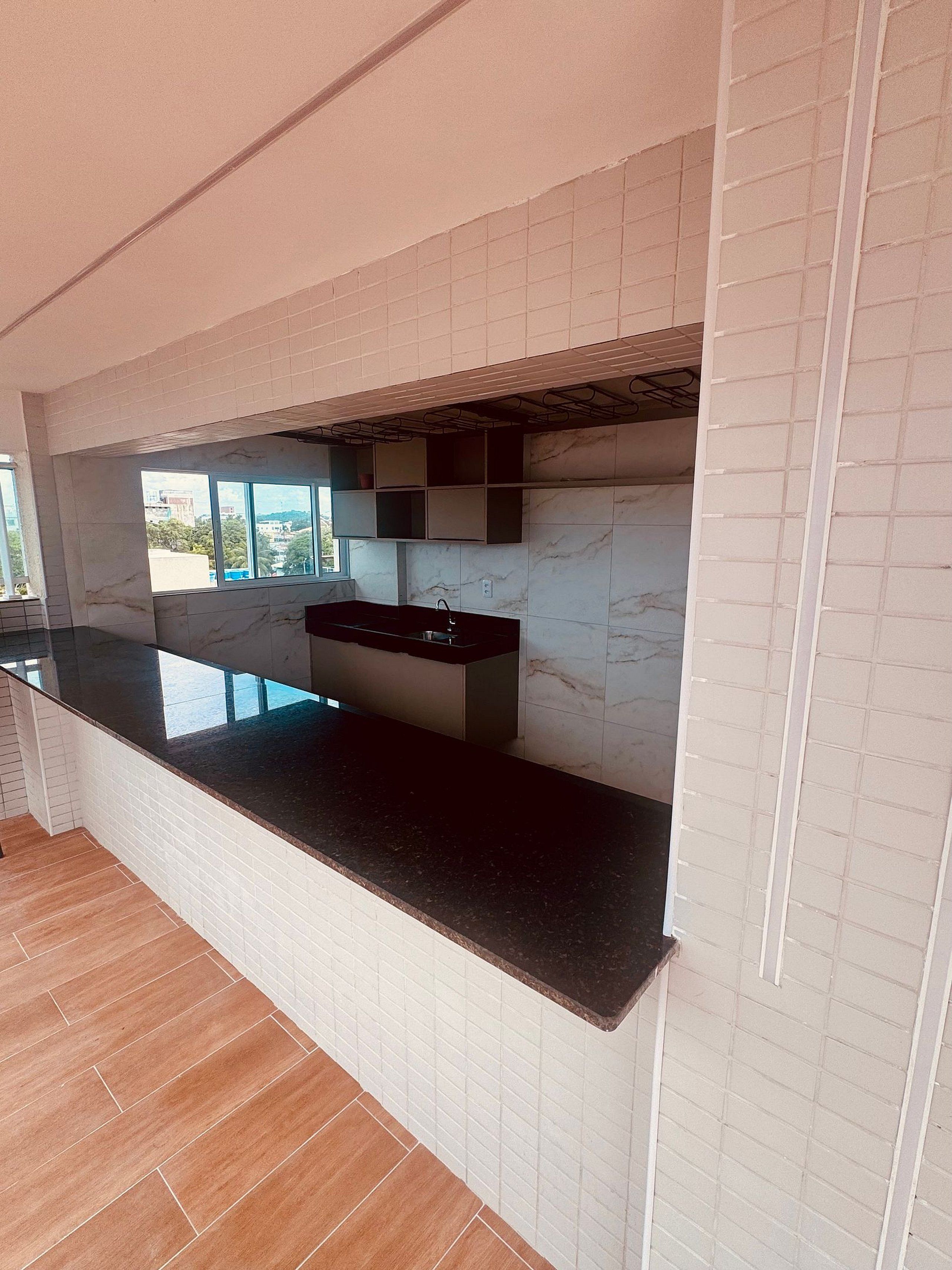 Una cocina moderna con cubierta negra, salpicadero de azulejos blancos y ventana con vistas al exterior.