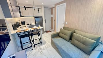 Um espaço de estar moderno com cozinha, sala de jantar e sofá.
