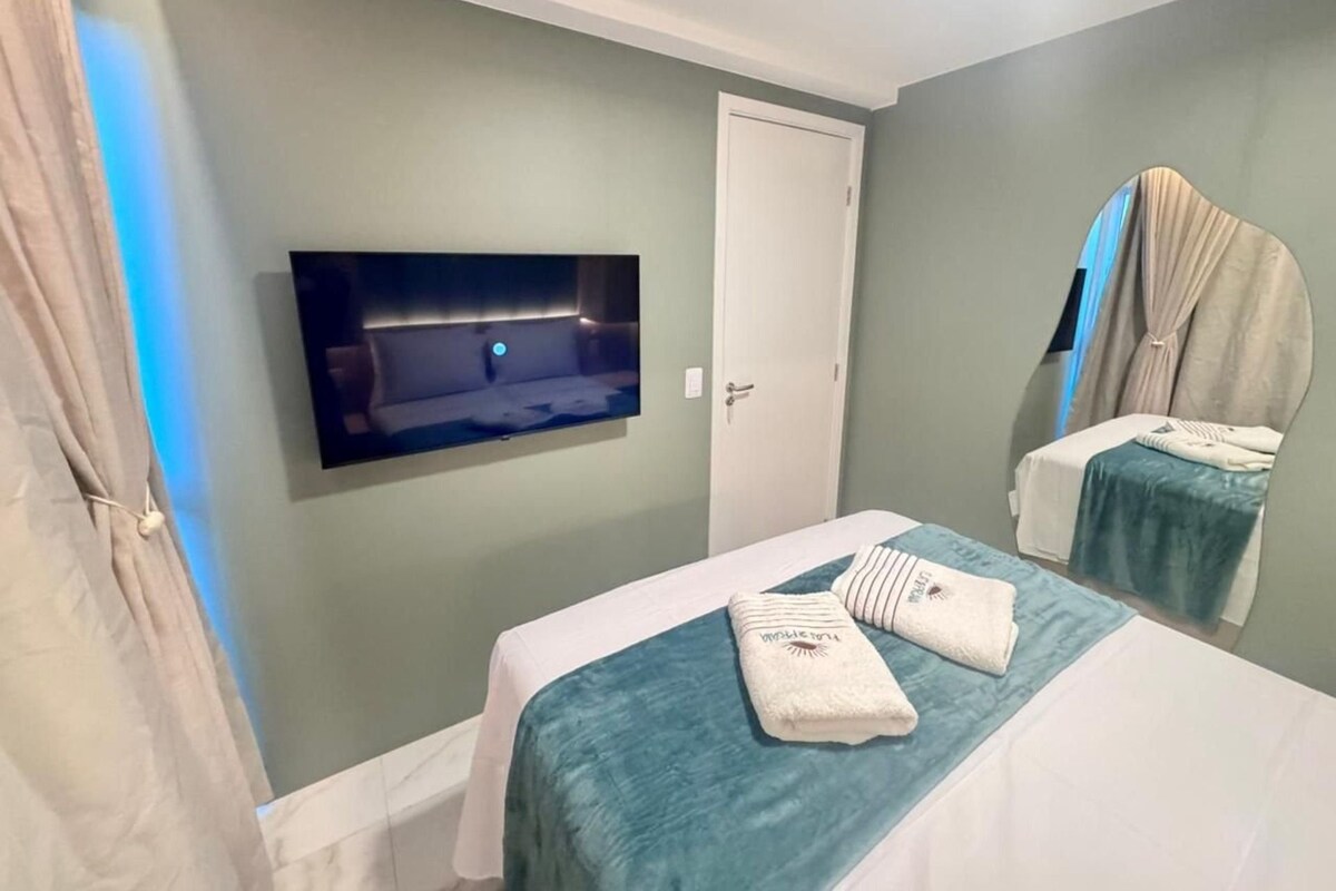 A hotel room with a bed, a television mounted on the wall, and a door.