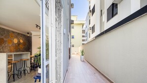 A narrow corridor with a bar area on the left, featuring stools and a potted plant. - Apt With Balcony and BBQ 30m From the sea Rdm0101 (Itapema)