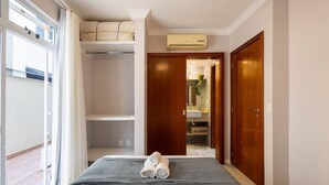 A hotel room with a bed, a wardrobe, a bathroom with a sink and mirror, and an air conditioning unit. - Apt With Balcony and BBQ 30m From the sea Rdm0101 (Itapema)