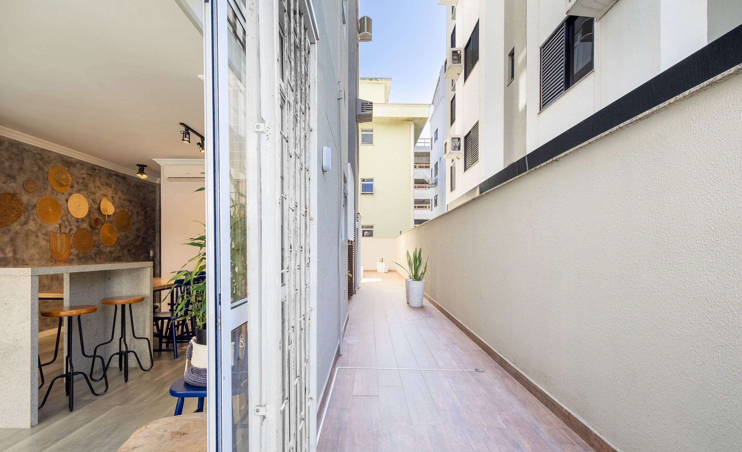 A narrow corridor with a bar area on the left, featuring stools and a potted plant.
