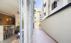 A narrow corridor with a bar area on the left, featuring stools and a potted plant. - Apt With Balcony and BBQ 30m From the sea Rdm0101 (Itapema)